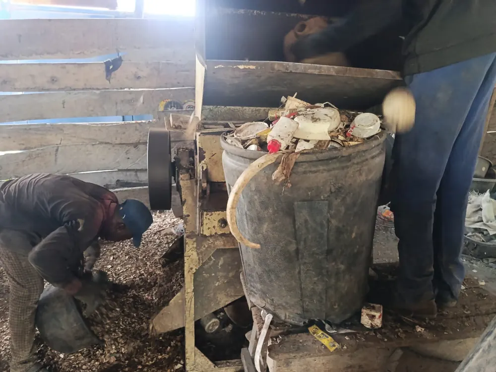 Workers feeding sorted plastic into a shredding machine